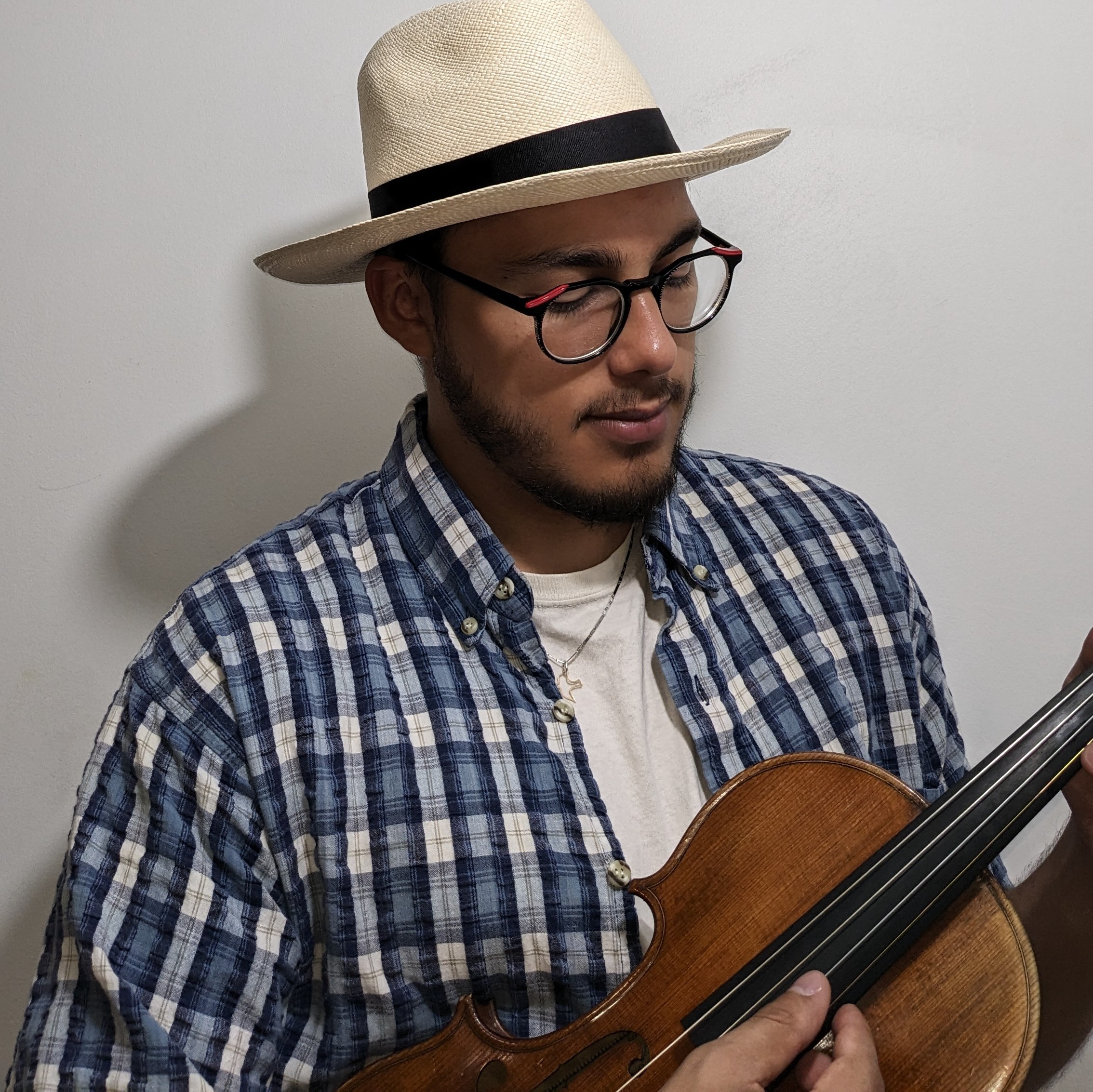 Josue Coy Dick wearing a straw hat and holding his violin