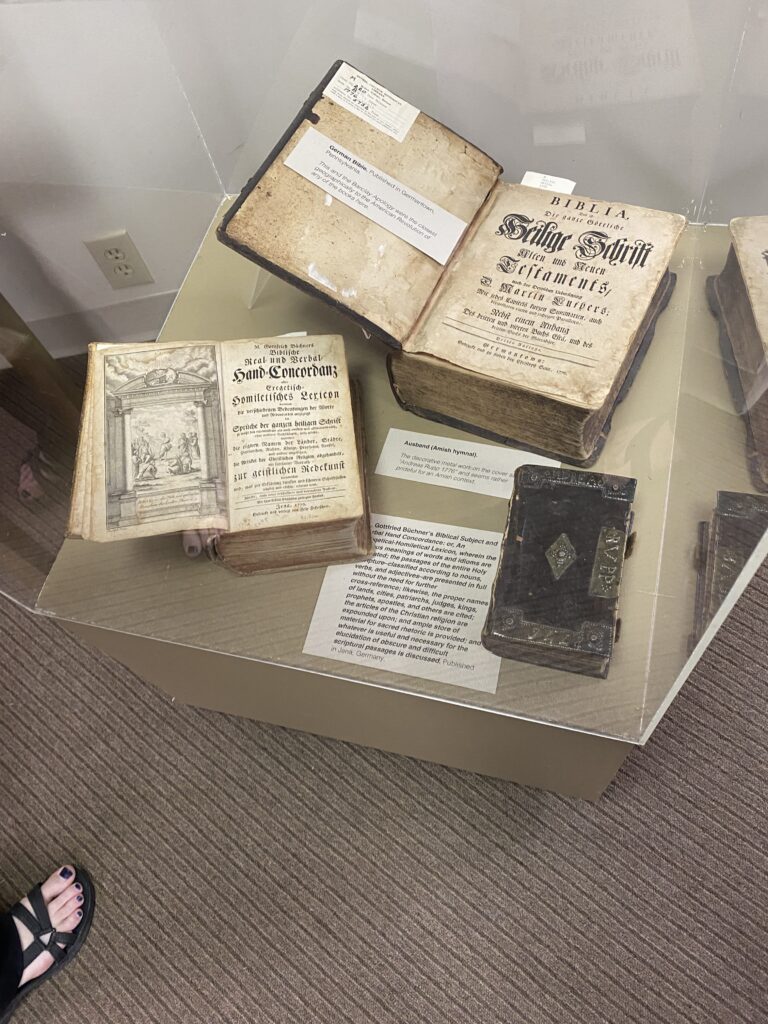 Three books inside a plexiglass display case, with identifying text.