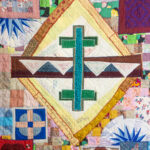 Detail of fabric art by Hattie Lee Mendoza, with a turquoise cross "reflecting" a second cross, with quilted designs around them