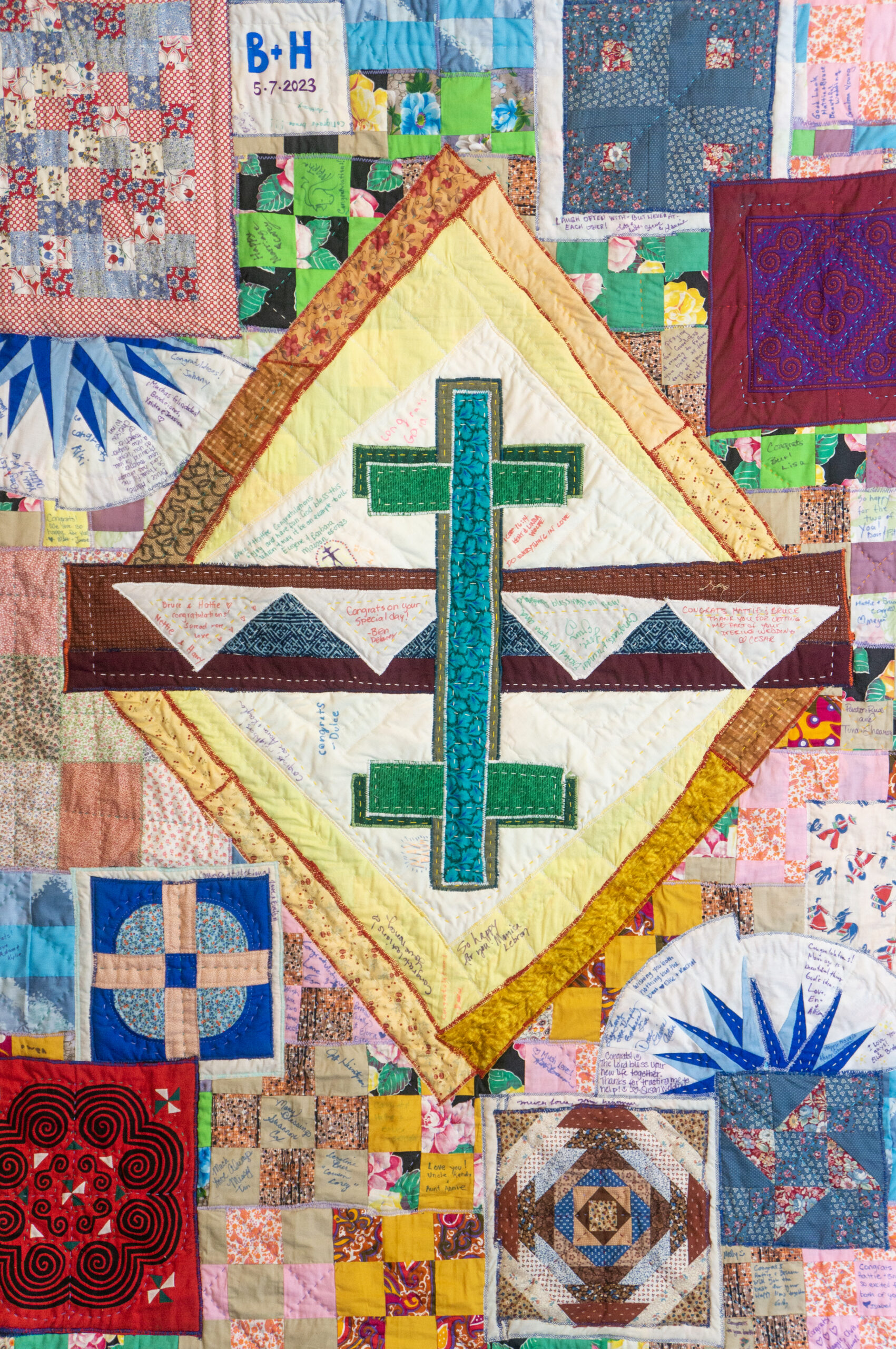 Detail of fabric art by Hattie Lee Mendoza, with a turquoise cross "reflecting" a second cross, with quilted designs around them