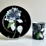 Painted china by Mary Lou Goertzen: a plate and cup with black background and blue and white flowers with green leaves
