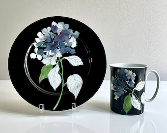 Painted china by Mary Lou Goertzen: a plate and cup with black background and blue and white flowers with green leaves